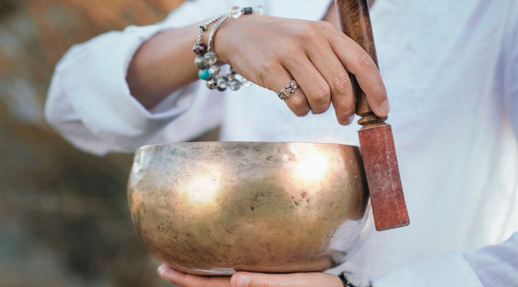 Woman with organic jewelry made from silver and stones creating sound bath healing with a sound bowl